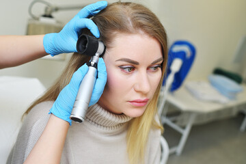dermatologist holds a dermatoscope in his hands and examines the structure of a young woman's hair. Trichoscopy is the science of hair structure.