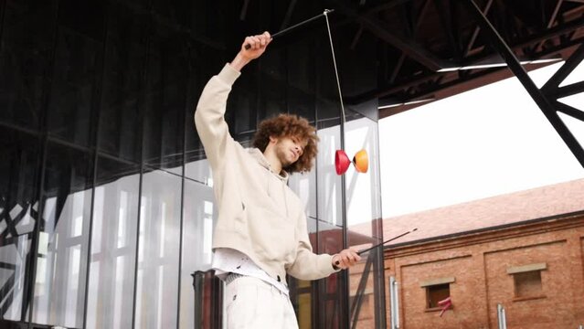 Young caucasian man doing tricks with diabolo game. Youth culture. Modern outdoors.