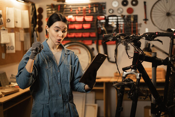 bicycle repair concept. Brunette woman using a digital tablet in a bicycle repair shop.