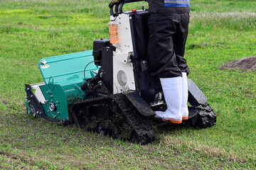 A person riding and operating a flail mower to mow the grass in the yard.