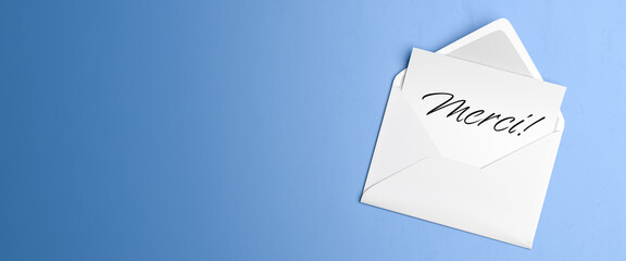 Letter with the text "Thank you" in an envelope on blue table background.