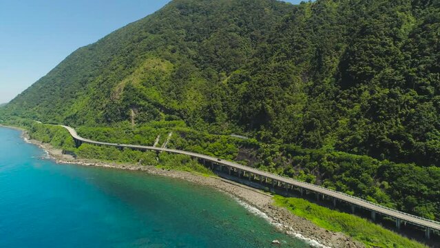 Aerial view of Patapat viaduct in the coast of Highway with bridge by coast sea near the mountains. Philippines, Luzon.