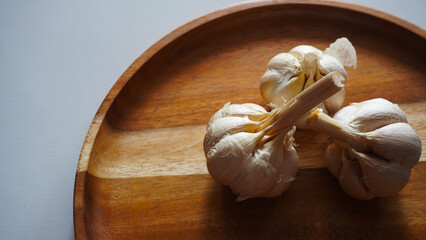 Isolated garlic or Allium sativum on a wooden tray. Selective focus                              - obrazy, fototapety, plakaty