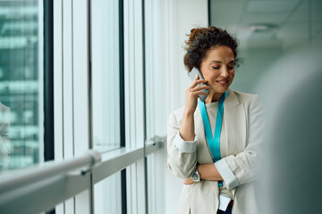 Smiling female CEO communicating on cell phone in office.