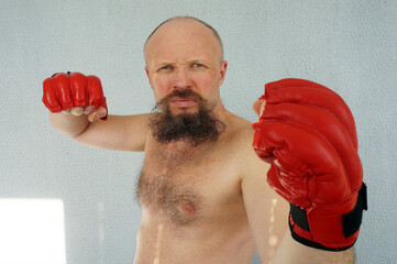 Boxer in red boxing gloves. Athlete, bodybuilder, athlete, muscle, sport, mma, fight, danger.                            Pugilist, mauler, pug, sparrer, prize-fighter