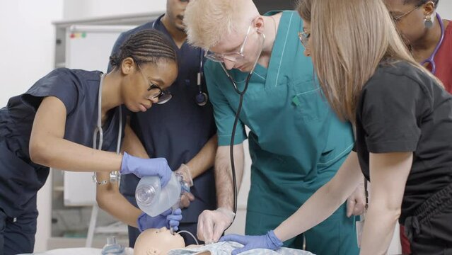 Group of nurses performing first aid on baby dummy
