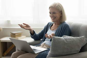 Laughing mature woman enjoy on-line talk with family living abroad using laptop and videoconference application, look at screen, share happy news, lead conversation spend time at home. Videocall event - obrazy, fototapety, plakaty
