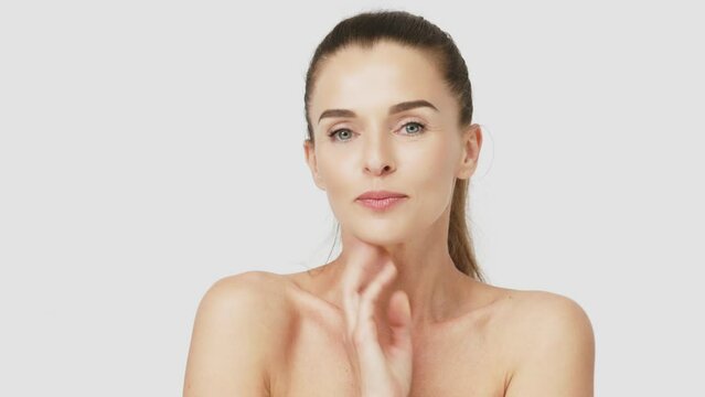 Happy mature middle-aged woman touching face and looking at camera. Healthy, dry skin care concept, cosmetics and anti-aging plastic surgery.