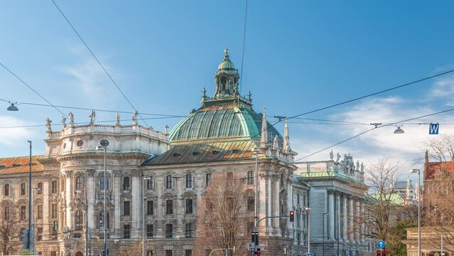 Exterior view of the Palace of Justice at the Karlsplatz timelapse in Munich, the capital of Bavaria, Germany. Traffic on the intersection with cars, buses and trams. Clouds on a blue sky