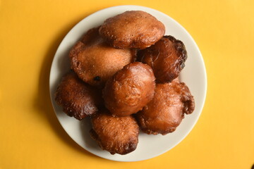 Sri Lankan Kevum dessert on white plate on yellow background, Awrudu Festival treats, sweets, deepfried food, Sinhala and Tamil New Year Food