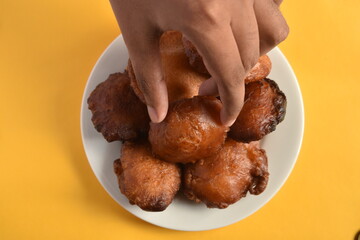 Sri Lankan Kevum dessert on white plate on yellow background, Awrudu Festival treats, sweets, deepfried food, Sinhala and Tamil New Year Food