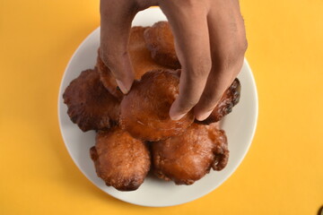 Sri Lankan Kevum dessert on white plate on yellow background, Awrudu Festival treats, sweets, deepfried food, Sinhala and Tamil New Year Food