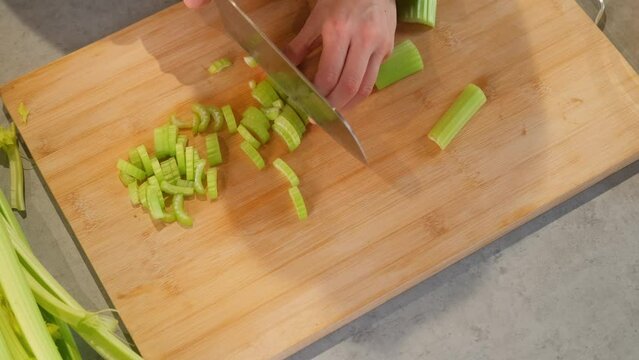 Close up video of woman cutting celery for vitamin salad in kitchen.