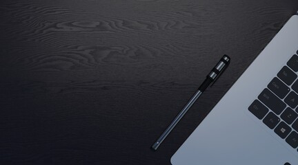 Copy space of pen and laptop on a black wooden desk