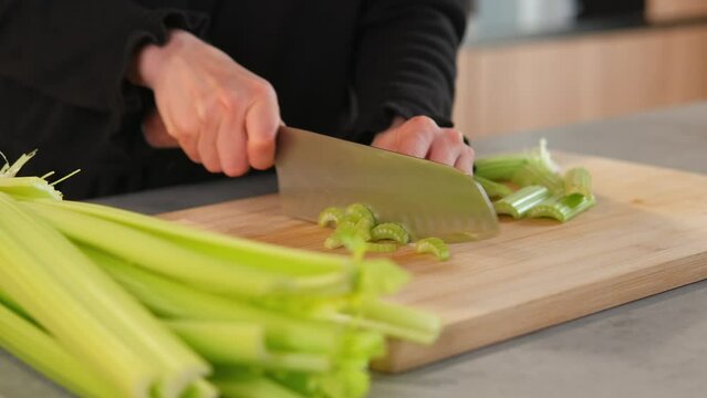 Close up video of woman cutting celery for vitamin salad in kitchen.
