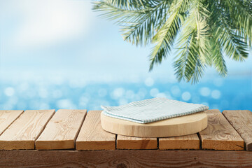 Empty wooden log with blue tablecloth on table over tropical beach bokeh background.  Summer mock up for design and product display.