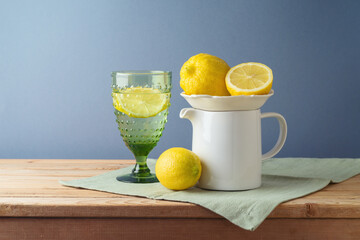Summer composition with lemons and white jug on kitchen wooden table