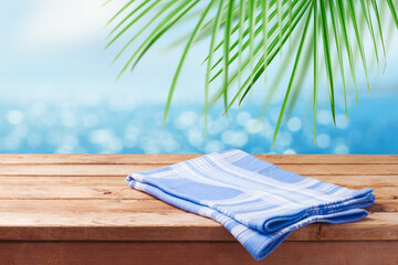 Empty wooden table with blue tablecloth over tropical beach bokeh background.  Summer mock up for design and product display.
