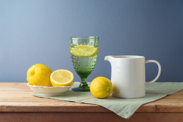Summer composition with lemons and white jug on kitchen wooden table - 783845481