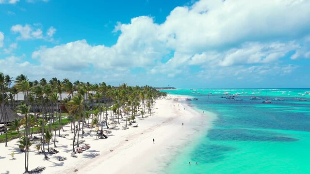 Aerial flight above white sand beach along palm trees and turquoise water of the Caribbean sea. Best all inclusive resort in Punta Cana. Top summer vacations destinations in the world