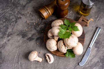 Fototapeta premium Raw white mushrooms champignons and pepper on grey background for cooking fresh ingredients. free copy space