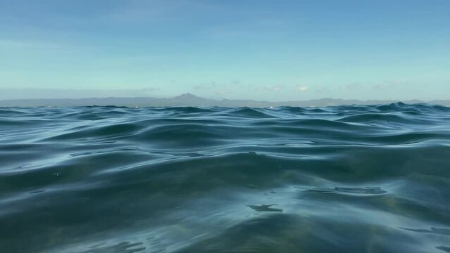 low angle shot of the sea against the background of mountains and sky. 