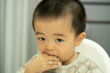 Close of baby boy eating rice with dirty right hand