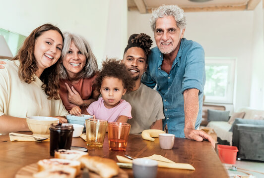 Portrait of a happy multigenerational family posing at breakfast table indoors at home.