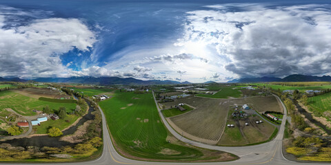 360 Aerial View of the Farms and Mountains. Dramatic Cloudy Sky.