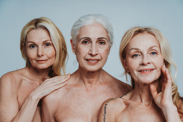 Image of three beautiful senior women posing on a beauty photo session. Middle aged women in lingerie holding hands close to face. Concept about body positivity, self esteem, and body acceptance. - obrazy, fototapety, plakaty