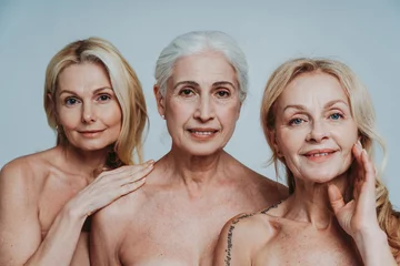 Fotobehang Image of three beautiful senior women posing on a beauty photo session. Middle aged women in lingerie holding hands close to face. Concept about body positivity, self esteem, and body acceptance. © oneinchpunch