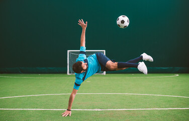 Cinematic image of a soccer freestyle player making tricks with the ball on a artificial grass...