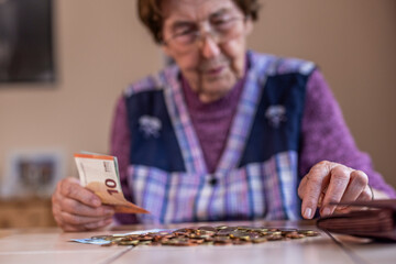 Seniorin zählt ihr Geld, Symbolbild für Armut und Altersarmut - obrazy, fototapety, plakaty