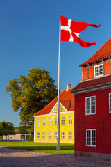 Danish flag waves over Royal Barracks at sunset in Copenhagen, Denmark, Kronprinsessegade Park