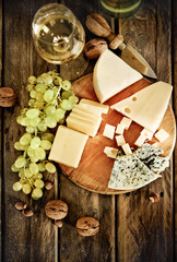 Bottles and glass of white wine, cheese, nuts and grapes