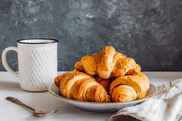 A plate of croissants and a cup of coffee sit on a table