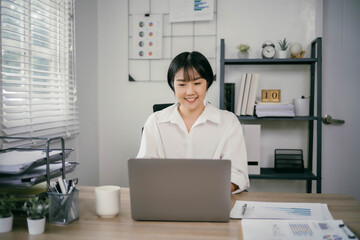 A woman is sitting at a desk with a laptop and a cup of coffee