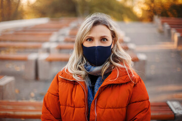Woman in mask and outerwear in park