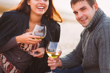 Young happy couple enjoying picnic with white wine on the beach