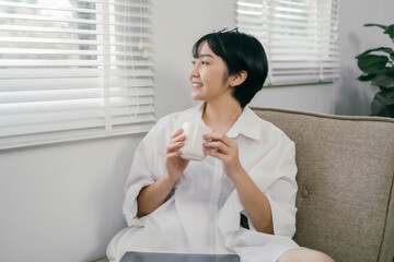 A woman is sitting on a couch with a cup of milk in her hand