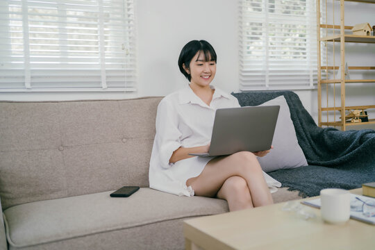 A woman is sitting on a couch with a laptop in front of her