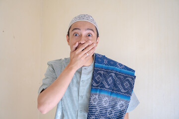 Moslem Asian man surprised expression looking to camera when Ramadan celebration. The photo is suitable to use for Ramadhan poster and Muslim content media.