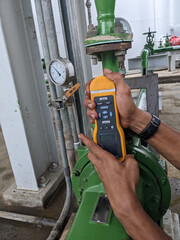Man worker measure vibration motor and pump on power plant project. The photo is suitable to use for industry background photography, power plant poster and electricity content media.