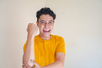Young man wear yellow t-shirt with strong pose expression gesture. The photo is suitable to use for man expression advertising and fashion life style.