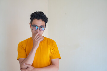 Young man wear yellow t-shirt with thinking pose expression gesture. The photo is suitable to use...