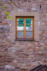 Reflection of a green blind on a window of a house with a rustic finish in Moia (Spain)