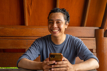 Man smile happy and surprised when looking at phone on the restaurant. The photo is suitable to use for expression advertising and ecommerce.