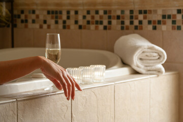 Woman Relaxing in the Bathroom Spa Tub with a Glass of Sparkling Champagne and Candles. - 783895273