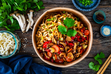 Takeaway food - Asian style stir fried vegetables and noodles on wooden table
