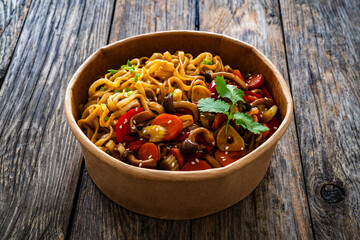 Takeaway food - Asian style stir fried vegetables and noodles on wooden table
